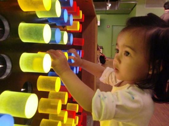 Child playing with luminescent cylinders at museum